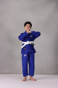 Child wearing a custom kids Jiu Jitsu Gi in the UK, blue Brazilian Jiu Jitsu uniform with a white belt on a gray background