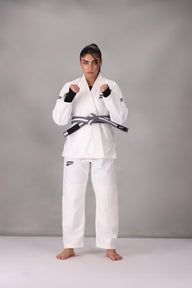 Woman wearing a custom white BJJ Gi with a black belt, standing on a gray background UK Brazilian Jiu Jitsu uniform