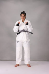 Woman wearing a custom white BJJ Gi with a black belt, standing on a gray background UK Brazilian Jiu Jitsu uniform