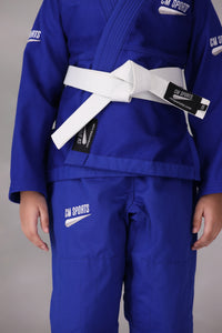 Child wearing a custom kids Jiu Jitsu Gi in the UK, blue Brazilian Jiu Jitsu uniform with a white belt on a gray background