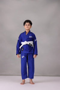 Child wearing a custom kids Jiu Jitsu Gi in the UK, blue Brazilian Jiu Jitsu uniform with a white belt on a gray background