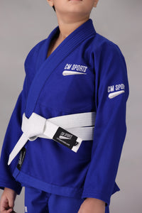 Child wearing a custom kids Jiu Jitsu Gi in the UK, blue Brazilian Jiu Jitsu uniform with a white belt on a gray background