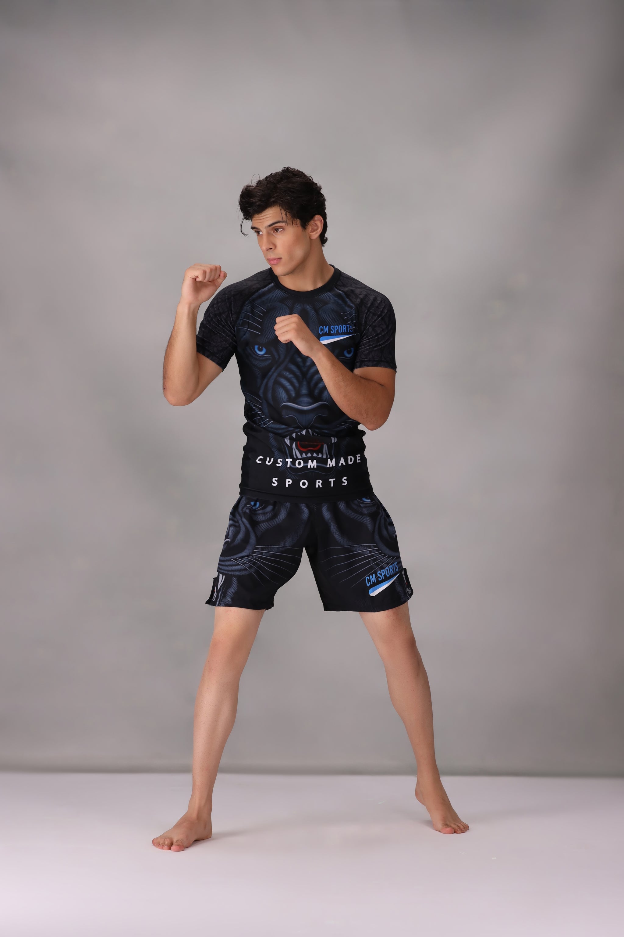 mma rashguards men wearing a black athletic outfit with Custom Made Sports branding on a gray background