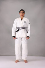 Woman wearing a custom white BJJ Gi with a black belt, standing on a gray background UK Brazilian Jiu Jitsu uniform