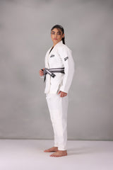 Woman wearing a custom white BJJ Gi with a black belt, standing on a gray background UK Brazilian Jiu Jitsu uniform